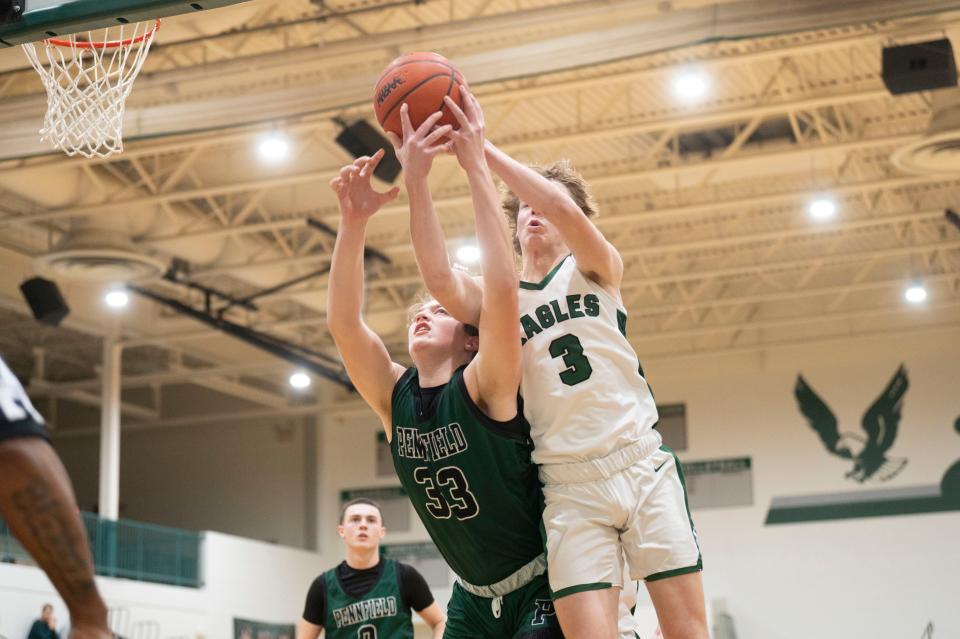 Olivet senior Tayven Feldpausch and Pennfield sophomore Johnathan Lake compete for a rebound during a game at Olivet High School on Tuesday, Jan. 30, 2024.