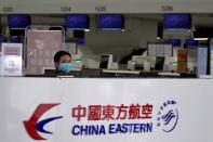 FILE PHOTO: Staff member wearing a face mask is seen behind a counter for China Eastern airlines at the Beijing Daxing International Airport, as the country is hit by an outbreak of the novel coronavirus, in Beijing