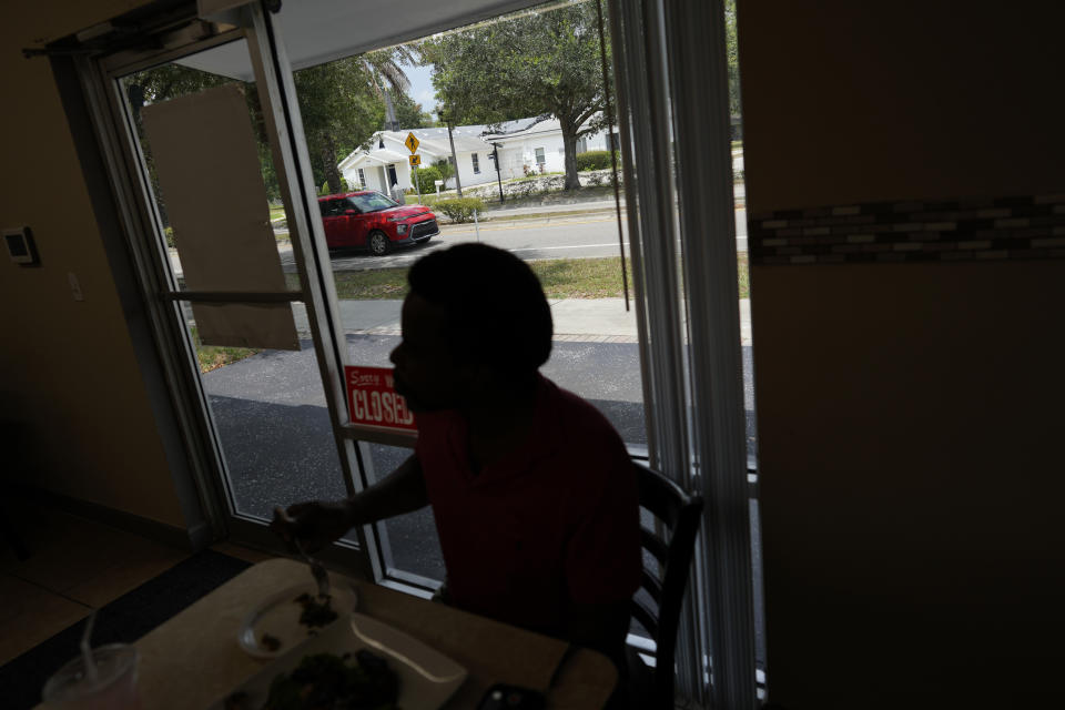 A customer has lunch at Tommy's Kitchen restaurant on East Kennedy Boulevard in Eatonville, Fla., Wednesday, Aug. 23, 2023. Seen across the street is St. Lawrence AME Church, a congregation founded in 1881 that predates the town's incorporation as a self-governing Black municipality in 1887. (AP Photo/Rebecca Blackwell)