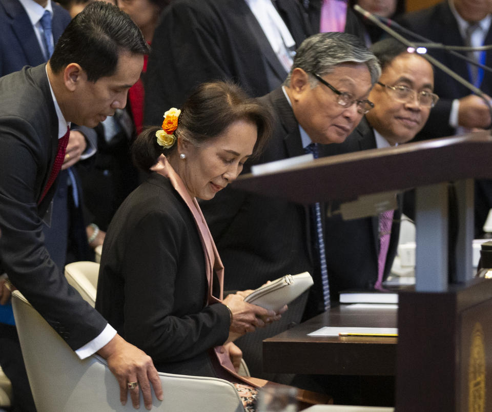 Myanmar's leader Aung San Suu Kyi takes her seat when entering the court room of the International Court of Justice for the first day of three days of hearings in The Hague, Netherlands, Tuesday, Dec. 10, 2019. Aung San Suu Kyi will represent Myanmar in a case filed by Gambia at the ICJ, the United Nations' highest court, accusing Myanmar of genocide in its campaign against the Rohingya Muslim minority. (AP Photo/Peter Dejong)