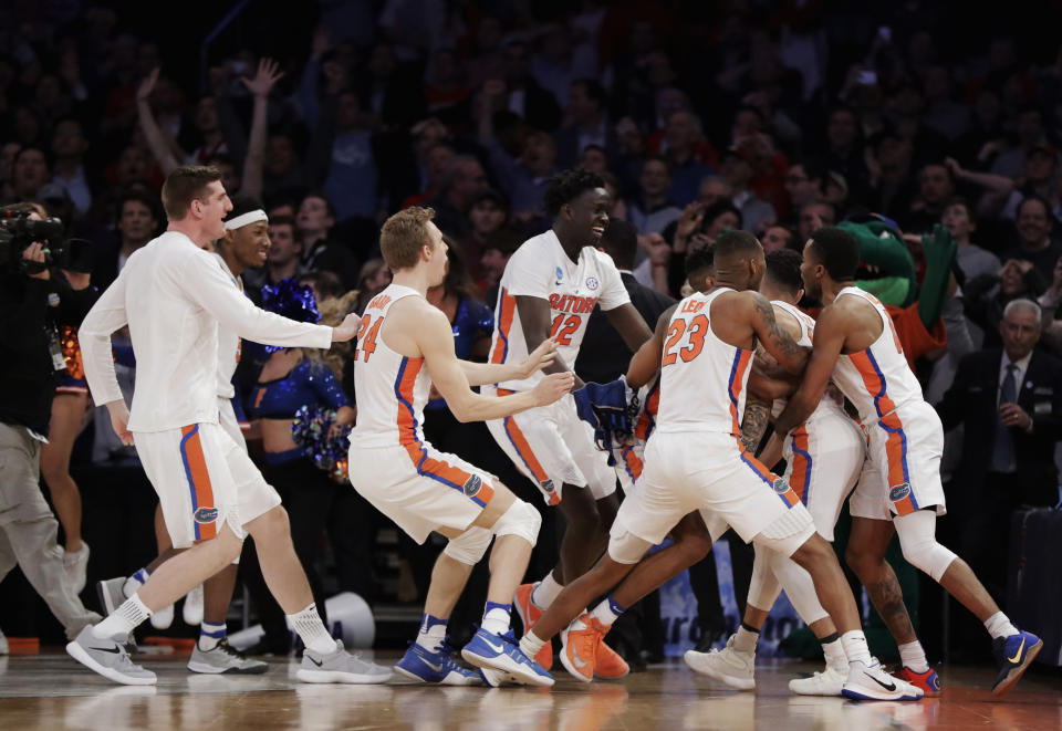 CORRECTS TO FLORIDA WINNING - Florida players celebrate after a last-second shot by guard Chris Chiozza (11) to beat Wisconsin in overtime of an East Regional semifinal of the NCAA men's college basketball tournament, early Saturday, March 25, 2017, in New York. Florida won 84-83. (AP Photo/Julio Cortez)