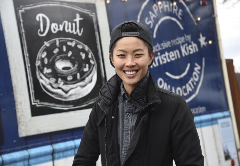 "Top Chef" winner Kristen Kish poses in front a food truck wearing a backwards cap and a layered jacket
