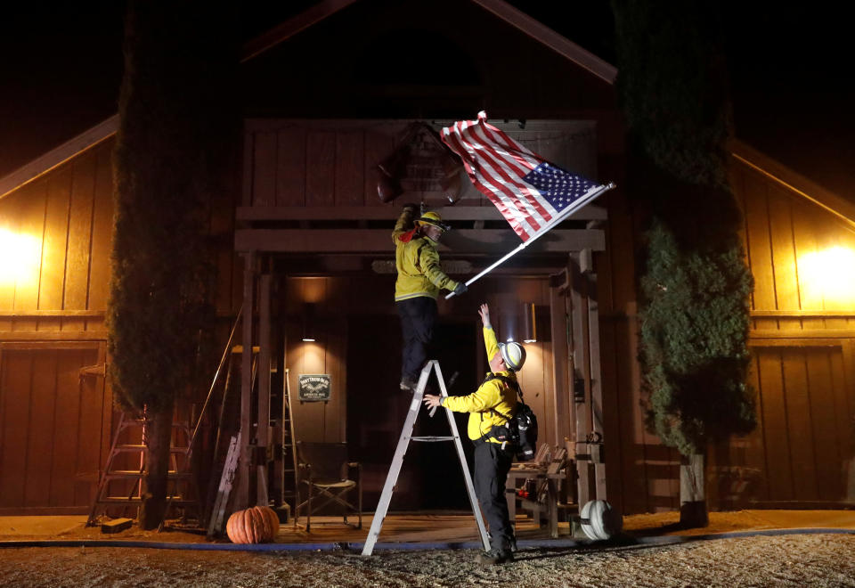 Firefighters remove a flag off a barn, as the wind driven Kincade fire burns near the town of Healdsburg, California, Oct. 27, 2019. (Photo: Stephen Lam/Reuters)