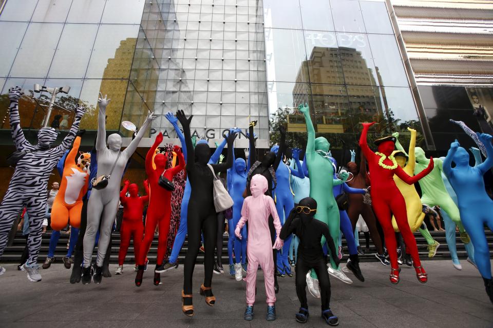 Participants wearing Zentai costumes pose for photos during a march down the shopping district of Orchard Road during Zentai Art Festival in Singapore