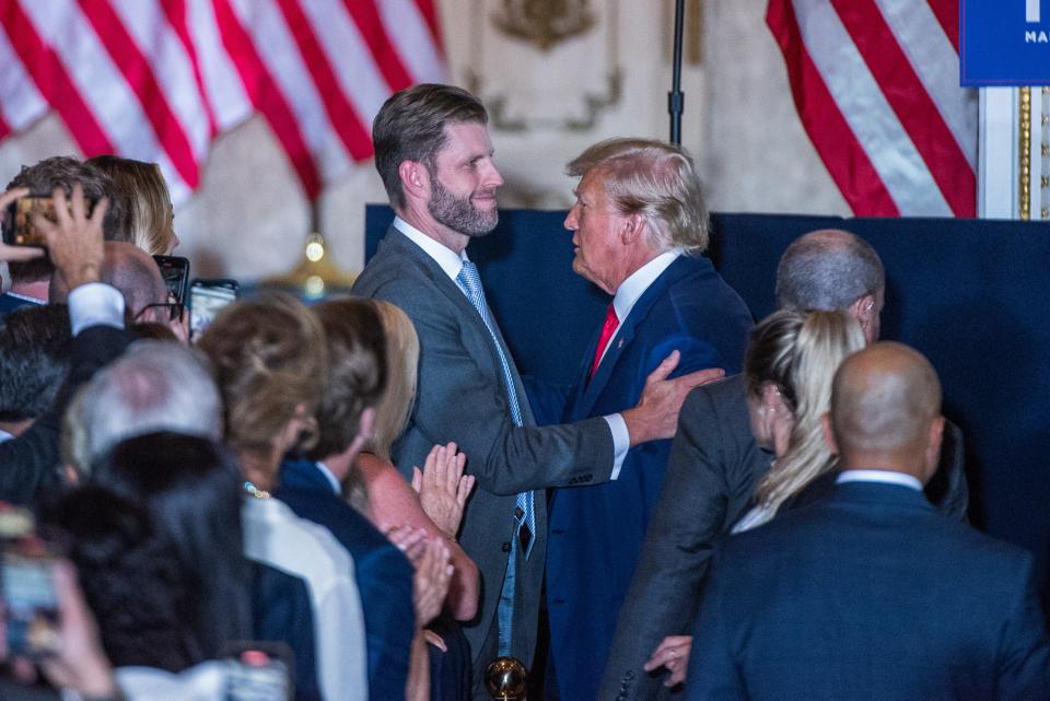 Eric Trump, son of former President Donald Trump, touches his father's shoulder as former President Trump arrives to a press event at Mar-A-Lago.