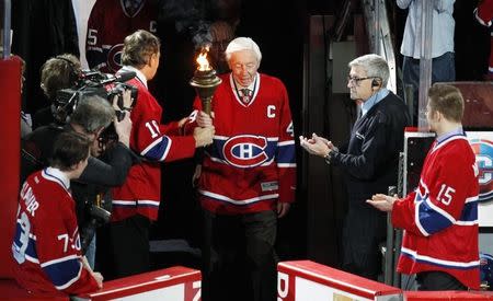 Former Montreal Canadiens NHL hockey player Jean Beliveau (C) is given a torch to carry before the season's opening game of the Montreal Canadiens against the Toronto Maple Leafs in Montreal, January 19, 2013. REUTERS/Christinne Muschi
