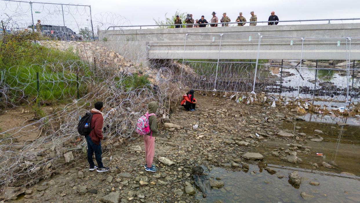 In an aerial view, U.S. soldiers and law enforcement officers stand over a small group of immigrants who had crossed the Rio Grande into the United States on March 18, 2024 in Eagle Pass, Texas.