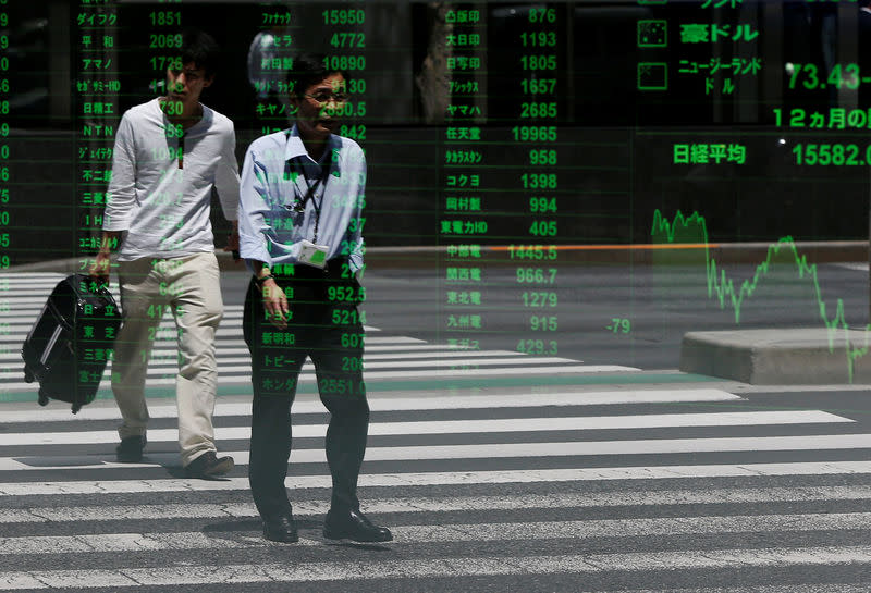 Passersby are reflected on a stock quotation board outside a brokerage in Tokyo, Japan July 11, 2016. REUTERS/Issei Kato