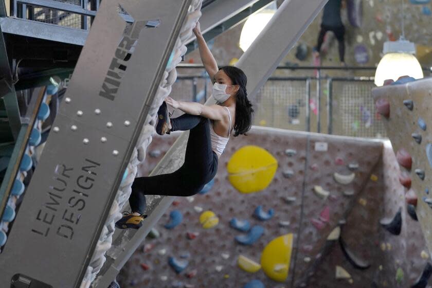 FILE - Gen Til wears a protective face mask while working out at Planet Granite climbing gym in San Francisco, March 4, 2021. Eleven San Francisco Bay Area counties will lift their mask requirements for vaccinated people in most indoor public settings beginning Feb. 16, 2022, when the state ends its indoor masking requirement for vaccinated people, officials announced Tuesday, Feb. 8. (AP Photo/Jeff Chiu, File)