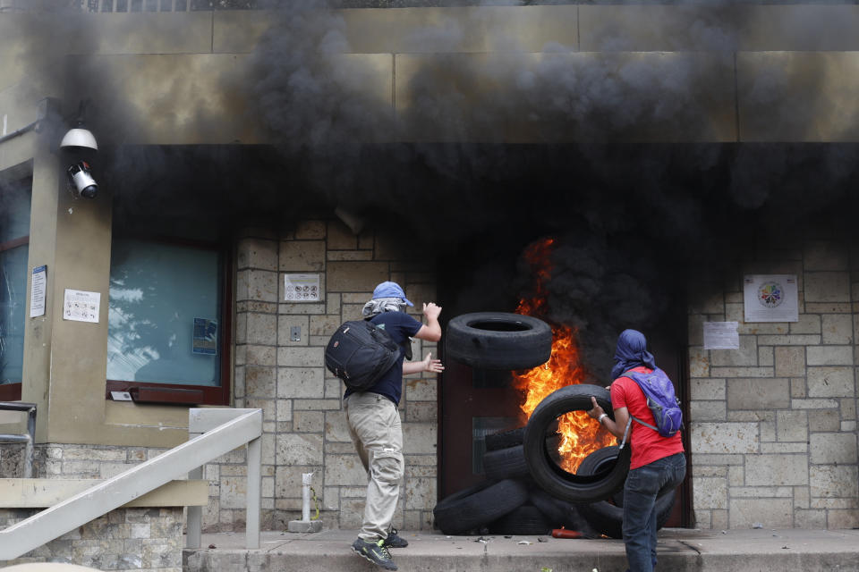 FILE - In this May 31, 2019 file photo, demonstrators burn tires at the U.S. embassy to protest the government of President Juan Orlando Hernandez in Tegucigalpa, Honduras. Three days after Hernández was labeled a co-conspirator with drug traffickers in August 2019, the top U.S. diplomat in Honduras tweeted that he had met with Hernández "to reaffirm the collaboration and cooperation between the U.S. and Honduras on important bilateral issues." (AP Photo/Elmer Martinez, File)