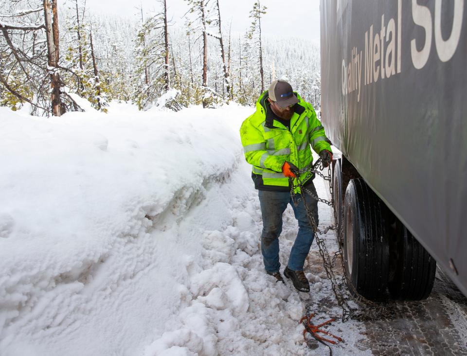 Cody Biancalana, from Eugene, takes chains off his semi-truck after making it through Santiam Pass east of Springfield.