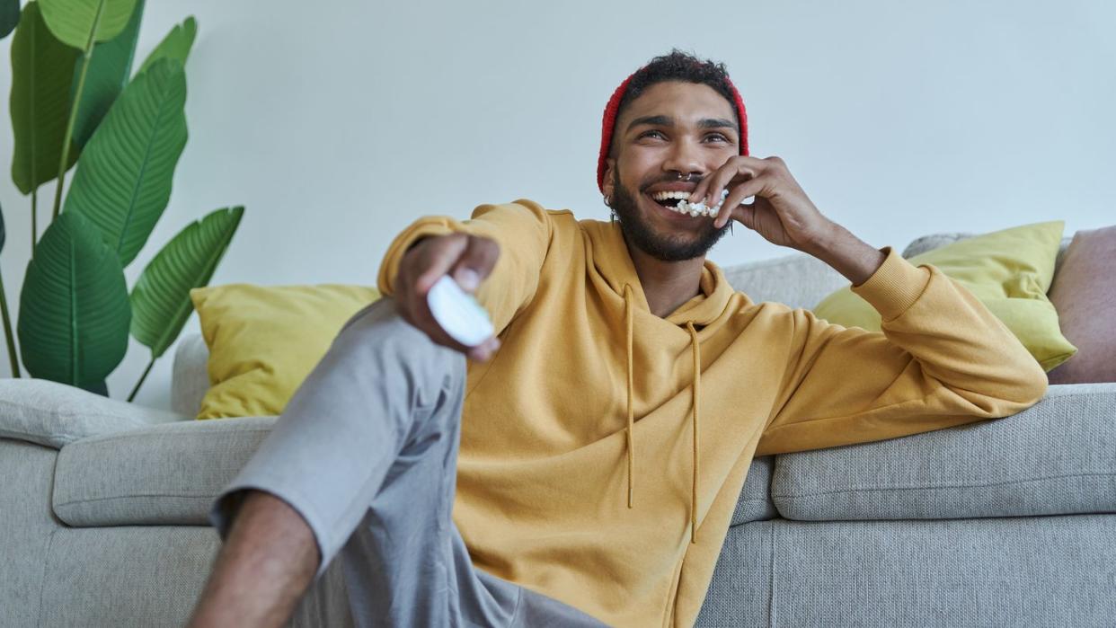 happy young man eating popcorn and watching tv