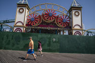 Pedestrians pass as construction continues in the amusement park district of Coney Island, Friday, June 17, 2022, in the Brooklyn borough of New York. Luna Park in Coney Island will open three new major attractions this season alongside new recreational areas and pedestrian plazas. (AP Photo/John Minchillo)