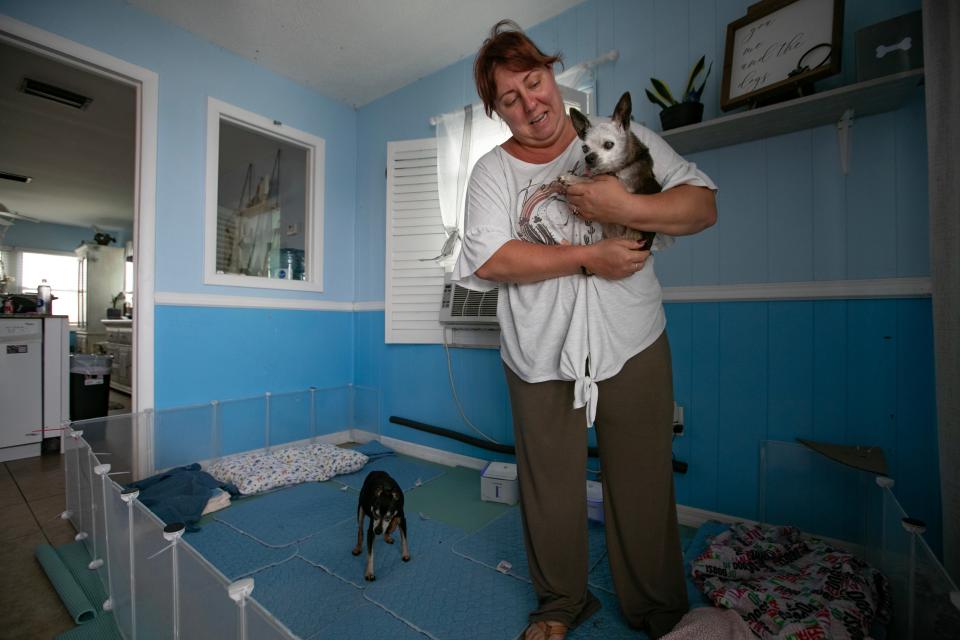 Matlacha resident Rachel Godbout, 42, hugs one of her dogs as she prepares to leave her home Tuesday morning, August 29, 2023. Her family was taking precautions due to the possibility of flooding and wind damage from the potential impact of Hurricane Idalia around the area.