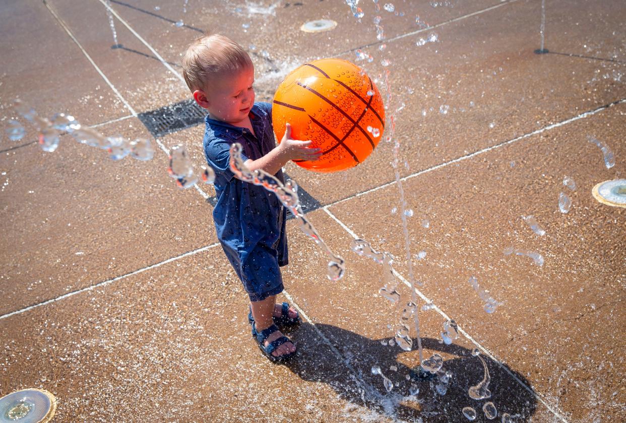 Theodore Patterson, 1, performs experiments blocking streams of water with a ball while beating the heat in the splash fountain at Southwind Park in Springfield on Aug. 24, 2021. The city could see a record high temperature today.