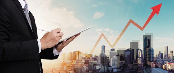 Businessman working digital tablet, with panorama city and raising arrow