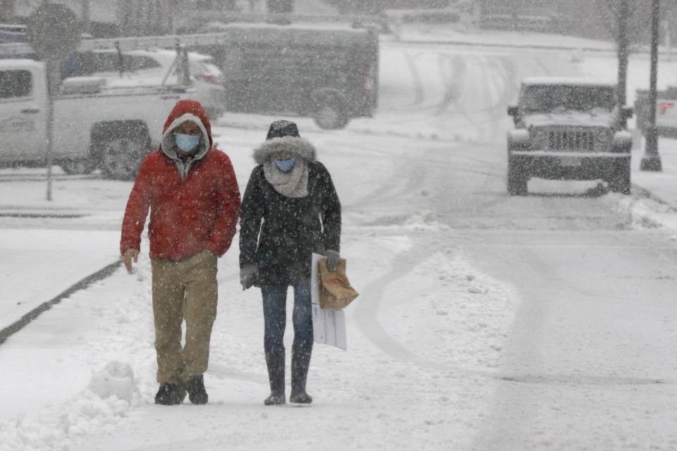 A couple walks through heavy snow, Saturday, Dec. 5, 2020, in downtown Marlborough, Mass. The northeastern United States is seeing the first big snowstorm of the season. (AP Photo/Bill Sikes)