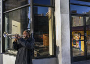 Street musician Roberto Hernandez, originally from El Salvador, plays "Lambada" on his trumpet outside Buddy's, a restaurant temporarily closed due to the COVID-19 pandemic, in downtown Los Angeles on Friday, Feb. 5, 2021. (AP Photo/Damian Dovarganes)