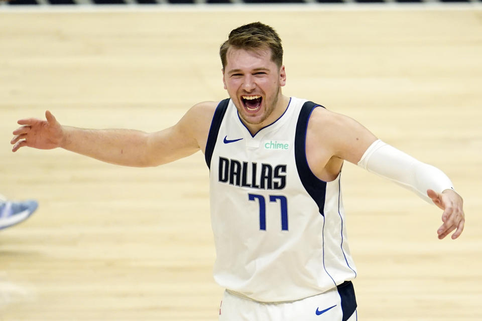 Luka Doncic stretches out his arms and smiles in celebration. 