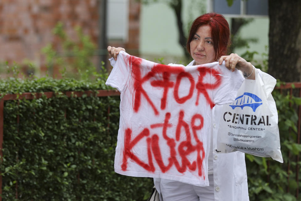 A woman holds a T-shirt reading: "KFOR the killer" in front of the city hall in the town of Zvecan, northern Kosovo, Wednesday, May 31, 2023. Hundreds of ethnic Serbs began gathering in front of the city hall in their repeated efforts to take over the offices of one of the municipalities where ethnic Albanian mayors took up their posts last week. (AP Photo/Bojan Slavkovic)