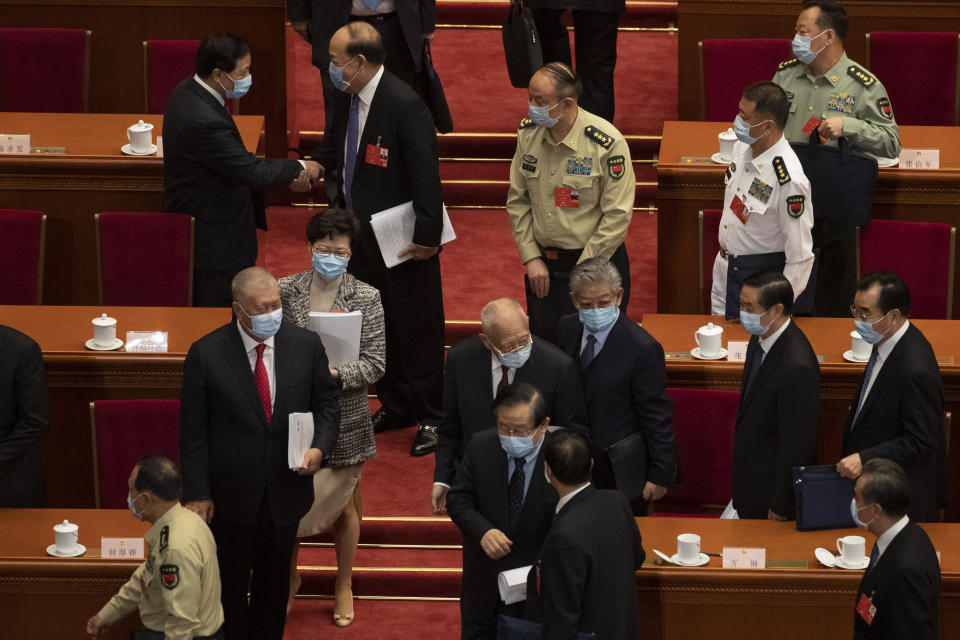 In this photo taken Friday, May 22, 2020,Hong Kong Chief Executive Carrie Lam, third from left leaves after attending the opening session of the National People's Congress held at the Great Hall of the People in Beijing. China is taking matters into its own hands after months of tumultuous anti-government protests in Hong Kong last year that often descended into tear gas and clashes. In a surprise move, the central government announced during the session that it would develop laws to outlaw secession, subversion of state power, terrorist acts and foreign interference in Hong Kong. (AP Photo/Ng Han Guan)