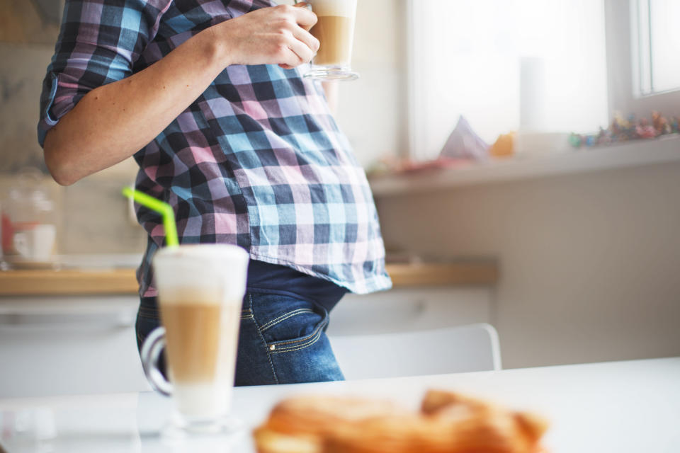 the girl is preparing morning coffee. pregnant girl drinks coffee by the window