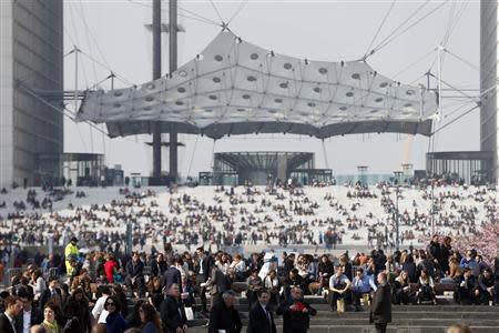 Businessmen enjoy the good weather at lunch time on the steps in front of the Arche de la Defense, in the financial and business district west of Paris, as warm and sunny weather continues in France, March 13, 2014. REUTERS/Charles Platiau