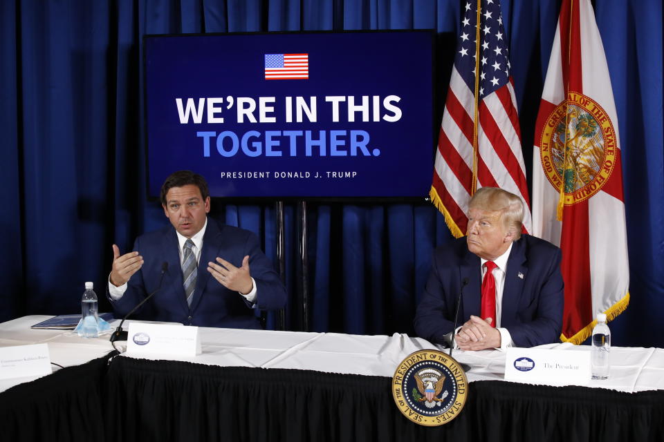 President Donald Trump listens as Florida Gov. Ron DeSantis speaks during a roundtable discussion on the coronavirus outbreak and storm preparedness at Pelican Golf Club in Belleair, Fla., Friday, July 31, 2020. (AP Photo/Patrick Semansky)