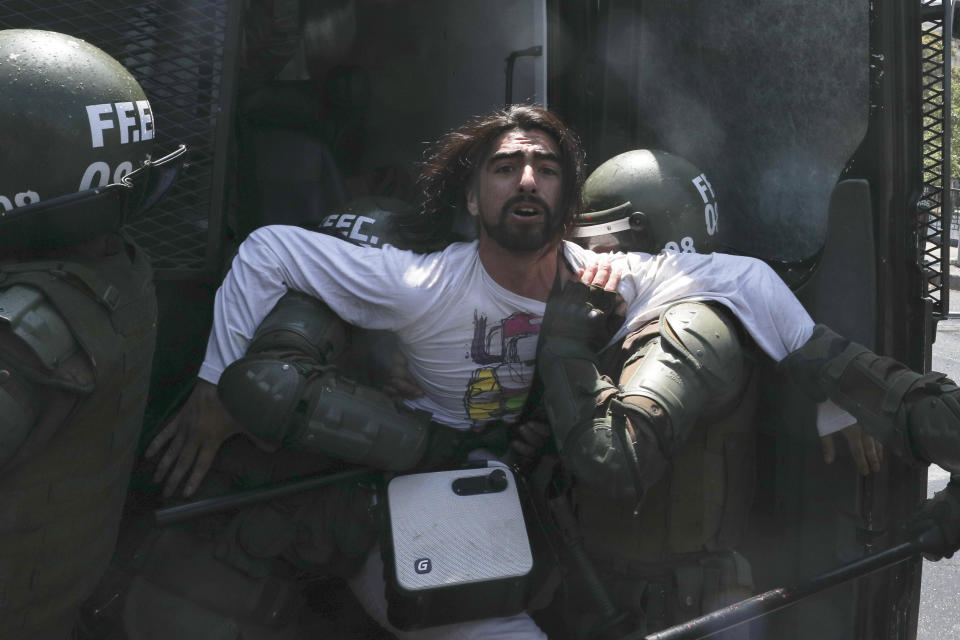 Police detain a demonstrator in Santiago, Chile, Sunday, Oct. 20, 2019. Protests in the country have spilled over into a new day, even after President Sebastian Pinera cancelled the subway fare hike that prompted massive and violent demonstrations. (AP Photo/Esteban Felix)