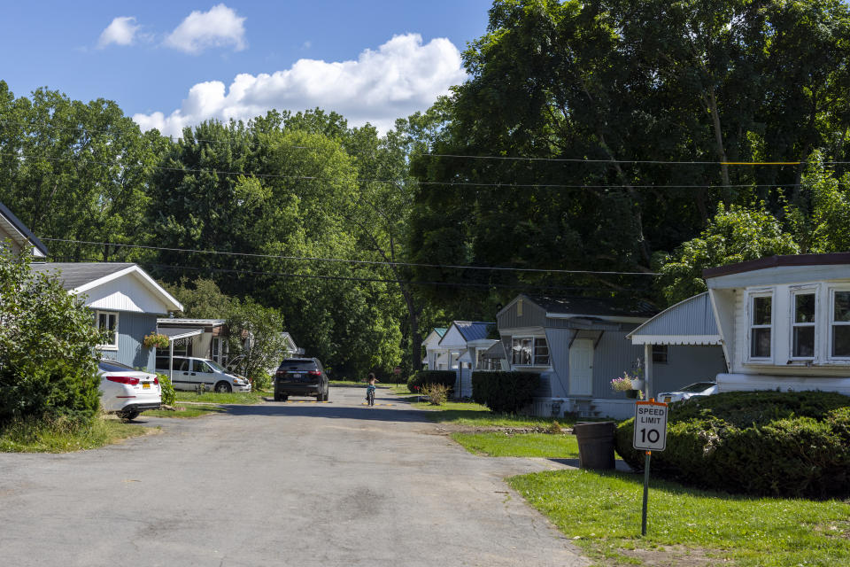 A child rides a bike down the street in the Ridgeview Homes mobile home community in Lockport, N.Y., June 23, 2022. Some of the residents in Ridgeview are participating in a rent strike as reaction to new owners of the community introducing a six percent rent increase. The plight of residents at Ridgeview is playing out nationwide as institutional investors, led by private equity firms and real estate trusts and sometimes funded by pension funds, swoop in to buy mobile home parks. (AP Photo/Lauren Petracca)