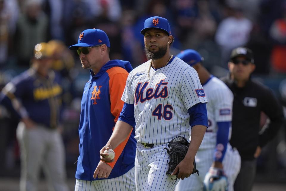 New York Mets relief pitcher Yohan Ramirez (46) leaves the game with manager Carlos Mendoza, left, after being ejected during the seventh inning of a baseball game against the Milwaukee Brewers, Saturday, March 30, 2024, in New York. (AP Photo/Frank Franklin II)