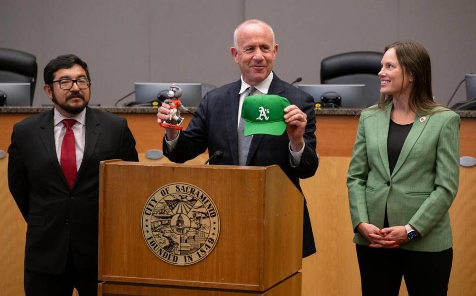 Sacramento Mayor Darrell Steinberg holds a Oakland Athletics baseball cap and a River Cats bobble head doll on Thursday during a press conference about the A’s move to West Sacramento with council members Eric Guerra and Caity Maple at Sacramento City Hall. Paul Kitagaki Jr./pkitagaki@sacbee.com