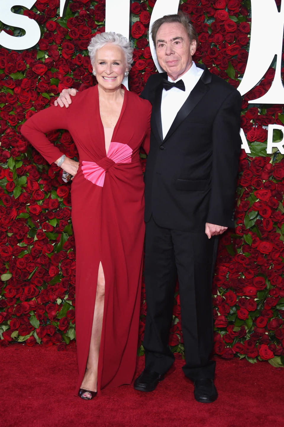 Glenn Close in a red dress and pink bow with Andrew Lloyd Webber 