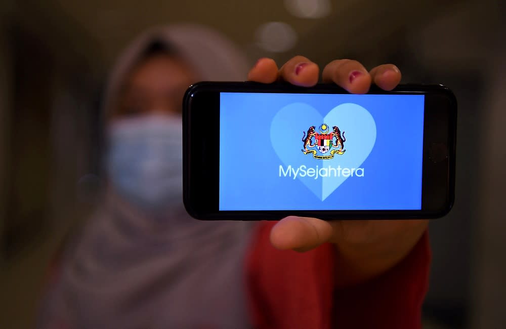 A woman holds up a phone displaying the MySejahtera app in Kuala Lumpur May 6, 2020. — Bernama pic