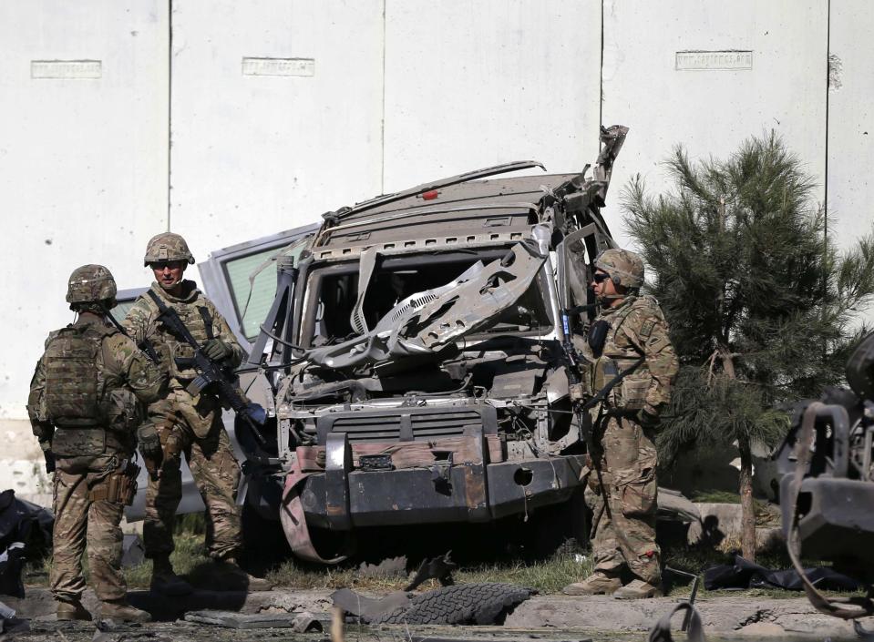 U.S. troops keep watch near a damaged vehicle at the site of a suicide attack in Kabul September 16, 2014. (REUTERS/Omar Sobhani)