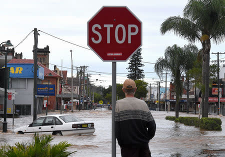 A local resident watches as floodwaters enter the main street of the northern New South Wales town of Lismore, Australia, March 31, 2017 after heavy rains associated with Cyclone Debbie swelled rivers to record heights across the region. AAP/Dave Hunt/via REUTERS