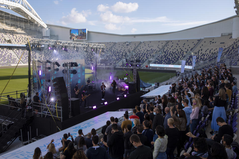 Israeli musician Ivri Lider perform in front of audience wearing protective face masks during a performance where all guests were required to show "green passport" proof of receiving a COVID-19 vaccination or full recovery from the virus at a soccer stadium in Tel Aviv, Friday, March. 5, 2021. (AP Photo/Oded Balilty)