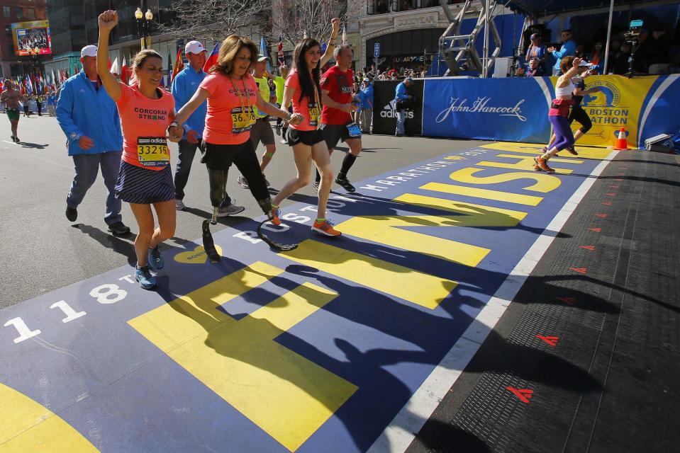 2013 Boston Marathon survivors Celeste (2nd L) and Sydney Corcoran (C) cross the finish line with Celeste's sister Carmen Acabbo, who ran the 118th Boston Marathon in Boston, Massachusetts April 21, 2014. REUTERS/Brian Snyder (UNITED STATES - Tags: SPORT ATHLETICS TPX IMAGES OF THE DAY)