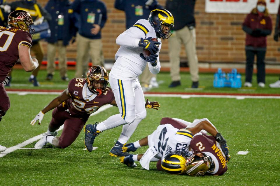 Michigan defensive lineman Donovan Jeter catches the ball en route to a touchdown past running back Mohamed Ibrahim after linebacker Michael Barrett knocked it loose from Minnesota quarterback Tanner Morgan in the first quarter on Saturday, Oct. 24, 2020, in Minneapolis.