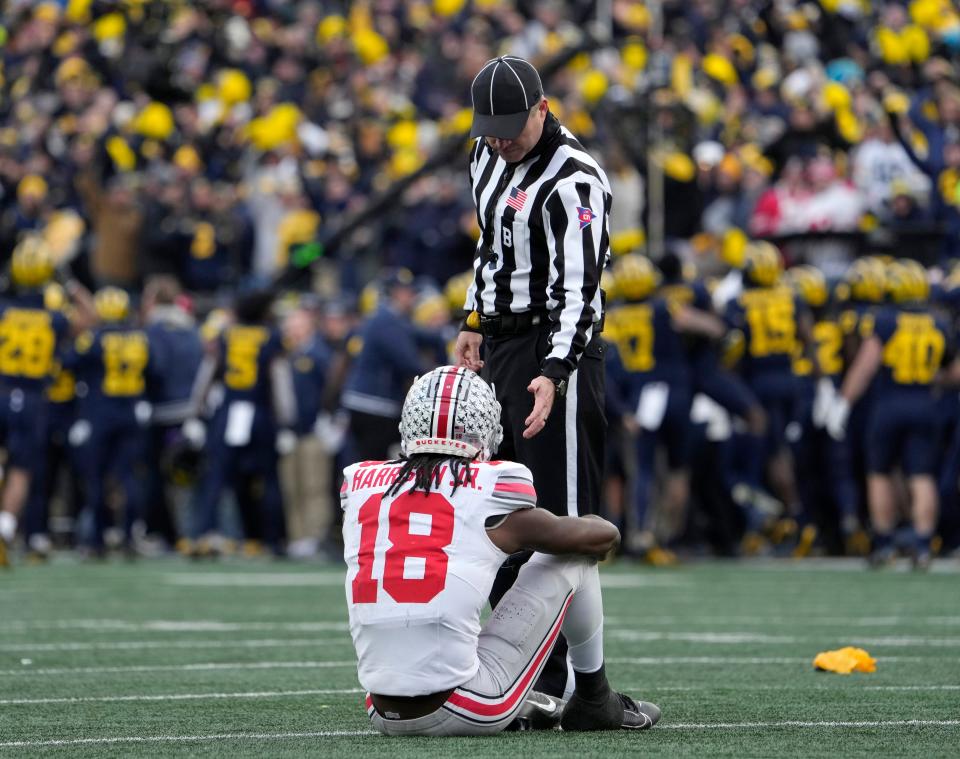 An official offers Ohio State receiver Marvin Harrison Jr. a hand during the second half of Saturday's loss at Michigan.