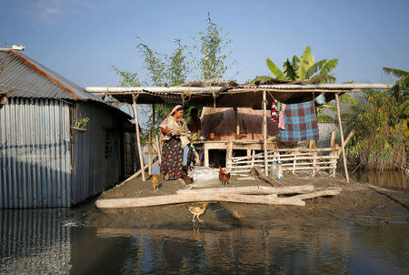 A woman and her family take temporary shelter on a piece of a dry land in their premises as their house has been flooded in Bogra, Bangladesh, August 20, 2017. REUTERS/Mohammad Ponir Hossain