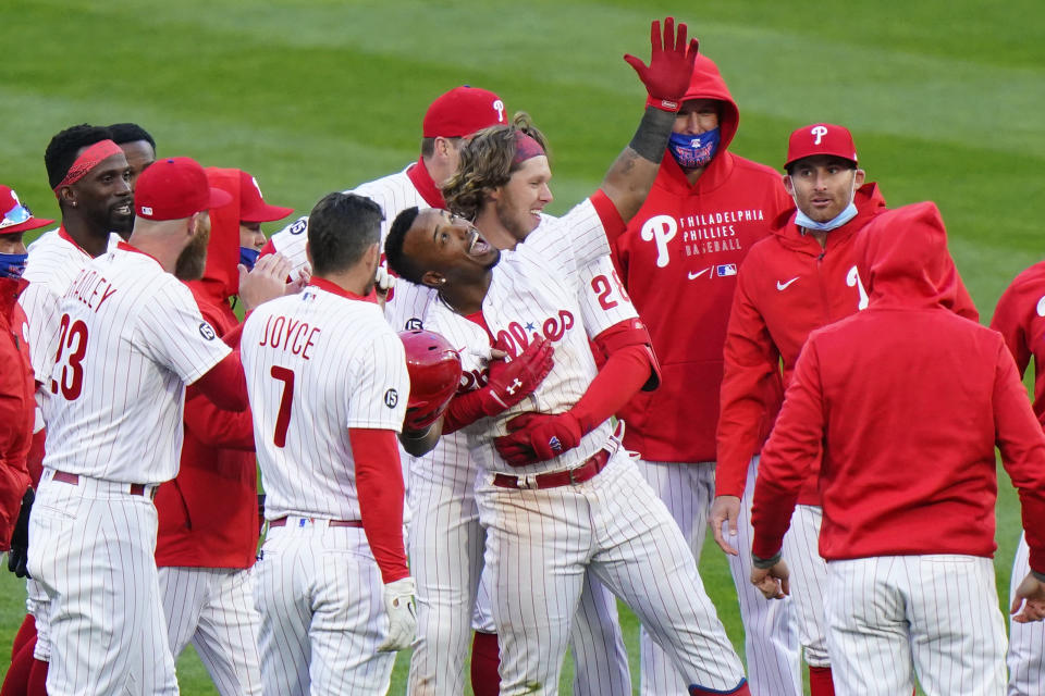 Philadelphia Phillies' Jean Segura, center, celebrates with teammates after hitting a game-winning RBI-single off Atlanta Braves relief pitcher Nate Jones during the 10th inning of an opening day baseball game, Thursday, April 1, 2021, in Philadelphia. (AP Photo/Matt Slocum)