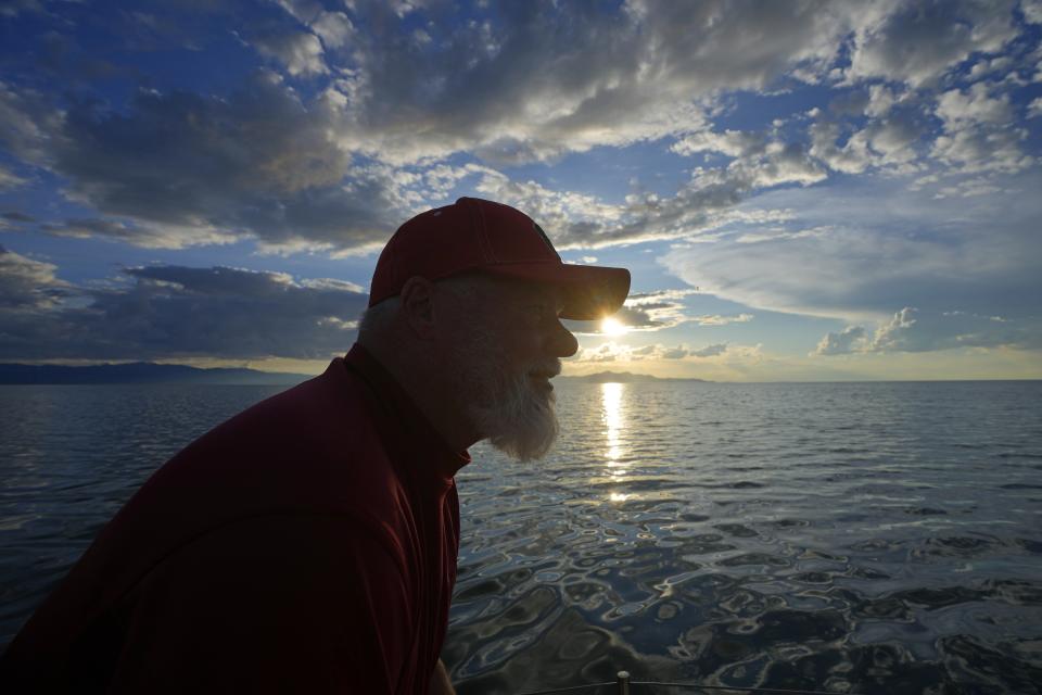 Randy Atkin looks out as the sun sets while sailing his boat through the Great Salt Lake on June 14, 2023, near Magna, Utah. Sailors back out on the water are rejoicing after a snowy winter provided temporary reprieve. (AP Photo/Rick Bowmer)