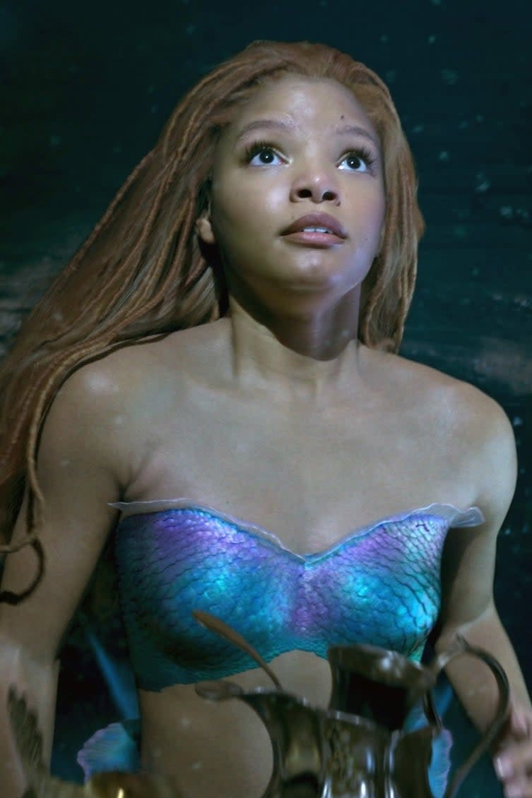 Ariel from The Little Mermaid swims underwater next to a fish, looking up towards the surface