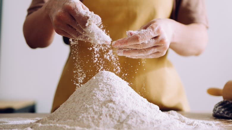 Hands working large pile of flour