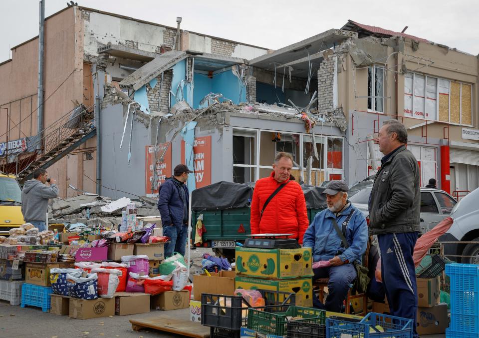 Market traders set up stalls by damaged buildings in Nova Kakhovka, Kherson (Reuters)