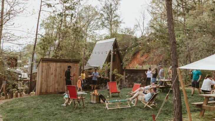 The backyard at Wrong Way River Lodge and Cabins, with people hanging out by fire pits on the grass