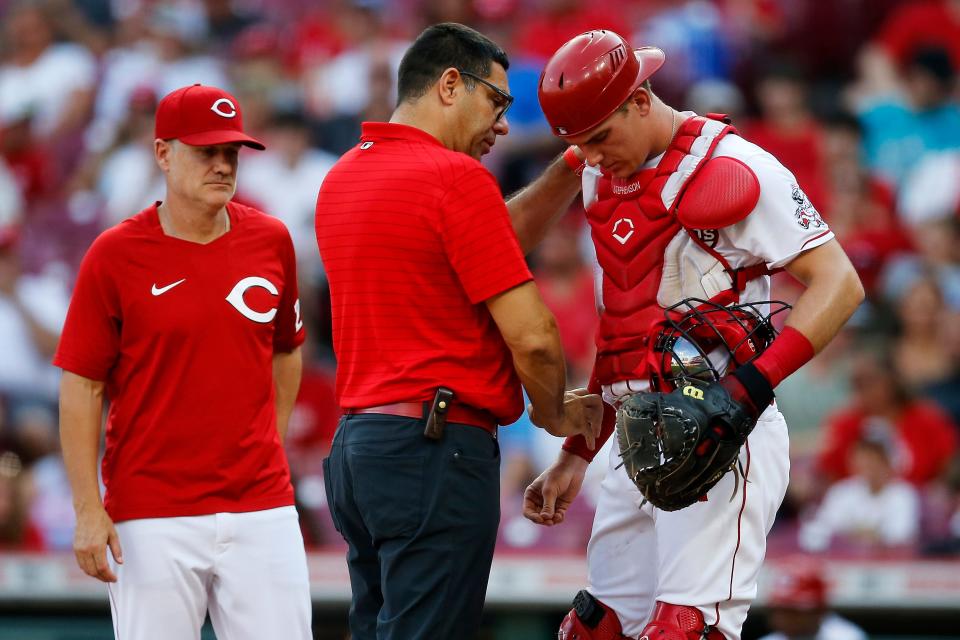 Cincinnati Reds catcher Tyler Stephenson (37) is examined by team trainer Tomas Vera after being hit in the arm by a foul ball in the first inning of the MLB National League game between the Cincinnati Reds and the St. Louis Cardinals at Great American Ball Park in downtown Cincinnati on Friday, July 22, 2022.