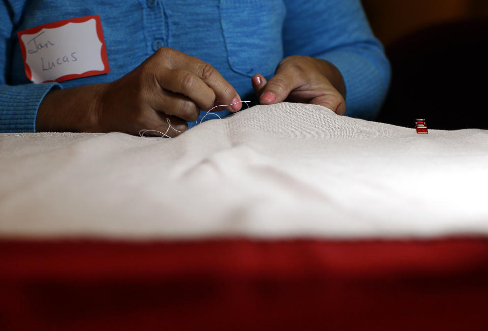 In this July 22, 2013 picture, volunteer Jan Lucas sews part of a replica of the star-spangled banner in Baltimore as part of a project to commemorate the creation of the flag that inspired America’s national anthem. The project began July 4 in Baltimore, and it is expected to take volunteers six weeks to hand sew the estimated 150,000 stitches in the famous flag. When finished, it will be about a quarter of the size of a basketball court. (AP Photo/Patrick Semansky)