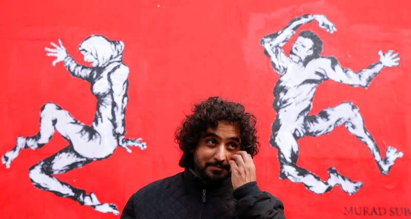 Yemen's street artist Murad Subay poses after unveiling a street painting to denounce the conflict in his country, in Paris